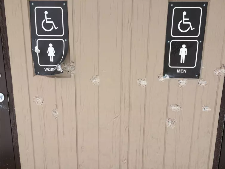 Concrete vault toilet restroom shows signs of damage.