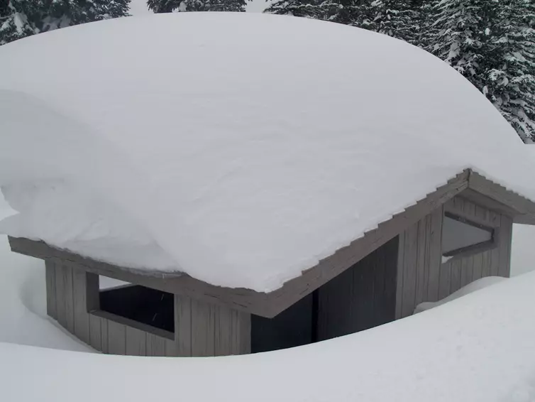 Vault toilet covered in snow.