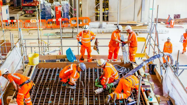Men wearing hi-vis working inside railway station.