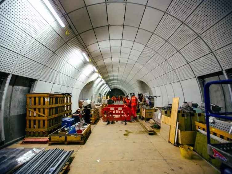 Homens com óculos de proteção trabalhando em um túnel subterrâneo.