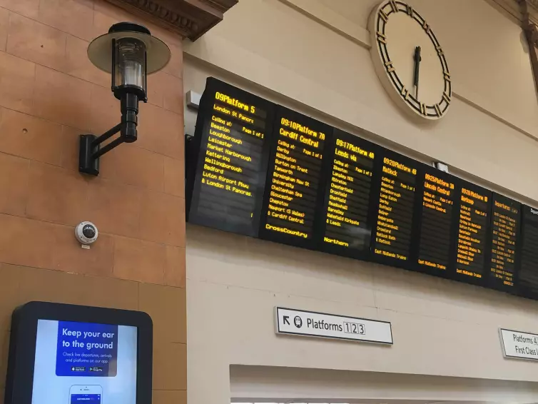Train information boards and clock in train station.