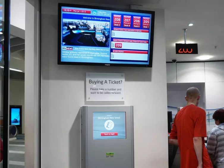 Informationsbildschirm und Fahrkartenautomat im Bahnhof.