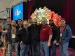 trois hommes en casques dorés souriant devant une scène avec un groupe au Precast Show