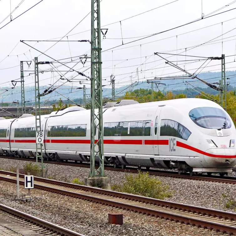 a white high speed train moving along a track at daytime.