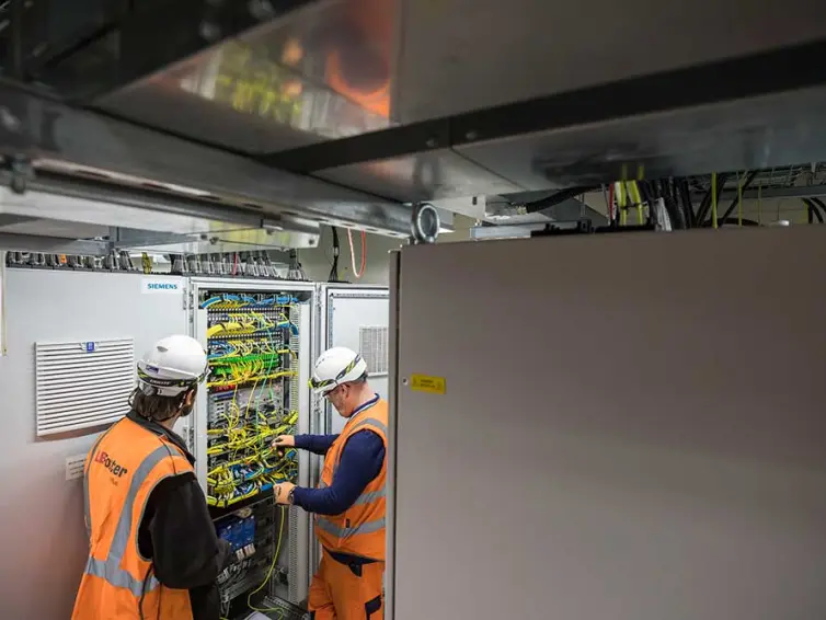 2 Männer bei der Installation von Telekommunikationsanlagen im Bahnhof.