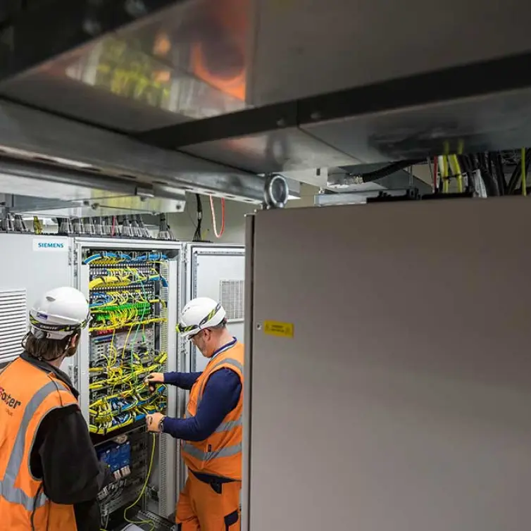 2 homens instalando equipamentos de telecomunicações na estação.