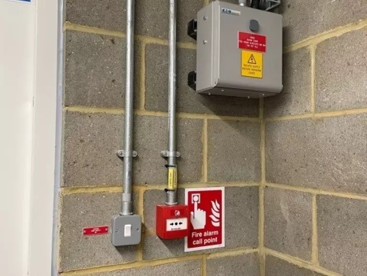 Fire alarm call point and light switch on a wall.