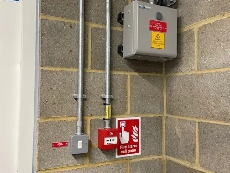 Fire alarm call point and light switch on a wall.