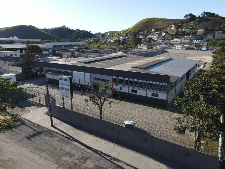 aerial photo of a factory building with mountains and houses in the background.