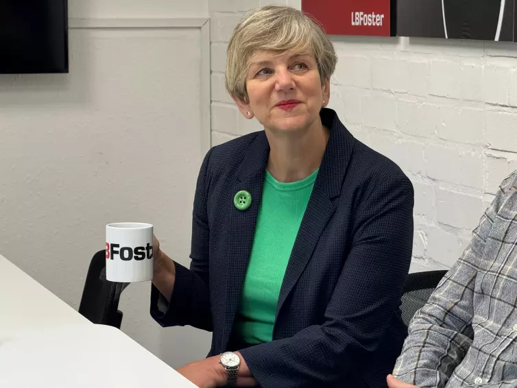 Lilian Greenwood, membro do Parlamento de Nottingham South, sorri com uma caneca de L.B. Foster na mão.