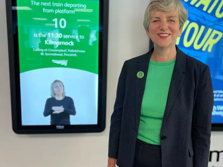 Lilian Greenwood, membro do Parlamento do Sul de Nottingham, sorri em frente ao Totem Informado de L.B. Foster com BSL.