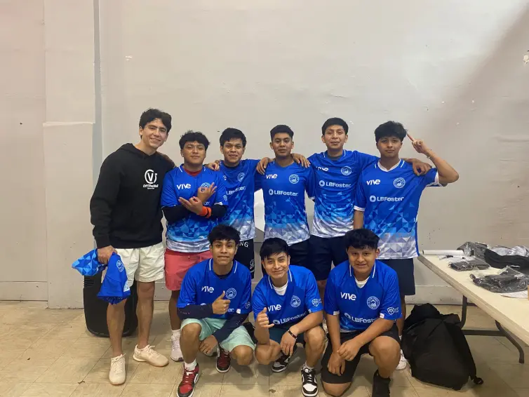 oito meninos e seu técnico vestindo camisetas azuis da marca L.B. Foster.