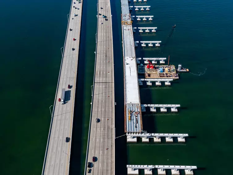 aerial image of a bridge being constructed over water next to a highway.