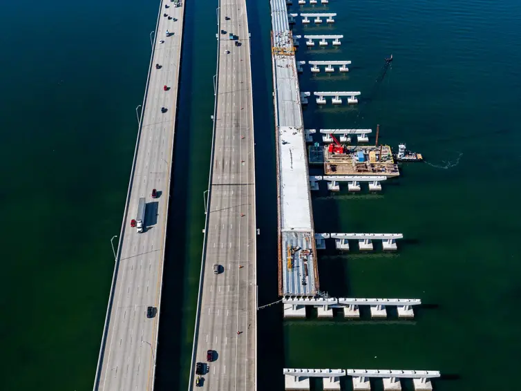 aerial image of a bridge being constructed over water next to a highway.