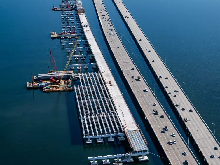 an aerial picture of a bridge being constructed on a waterway next to a highway.