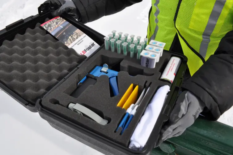 Opened box showing kit with surface cleaner, applicator gun, filler adhesive, sprayer with dipping tool, mixing nozzle, resealable dispensing bags, spreader, dusting brush, and cloth rags.