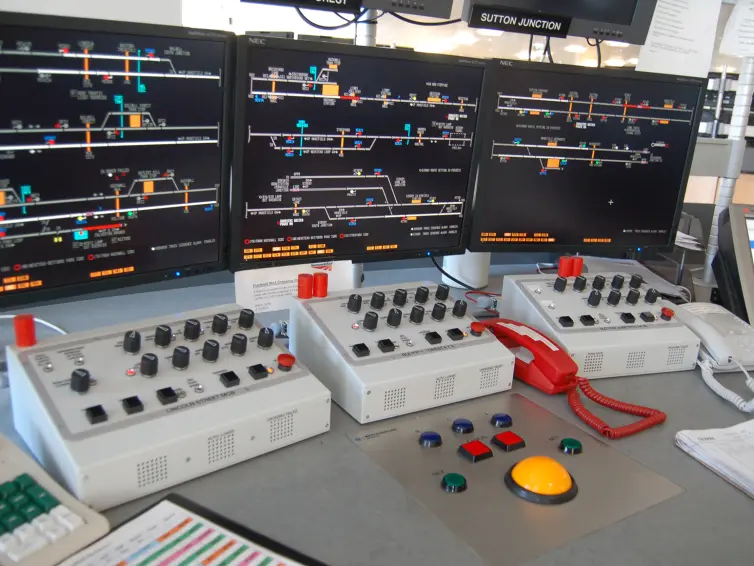 3 Bildschirme in einem Eisenbahnkontrollraum.