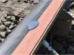 Nahaufnahme eines Eisenbahngleises, auf dem eine Pfütze mit einer violett-grauen Flüssigkeit auf einer orangefarbenen Schaumstoffstange zu sehen ist, die an der Schiene befestigt ist