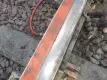 Nahaufnahme eines Eisenbahngleises, auf dem eine Pfütze mit klarer Flüssigkeit auf einer orangefarbenen Schaumstoffstange zu sehen ist, die an der Schiene befestigt ist