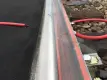 Nahaufnahme eines Eisenbahngleises, auf dem eine Pfütze mit klarer Flüssigkeit auf einer orangefarbenen Schaumstoffstange zu sehen ist, die an der Schiene befestigt ist