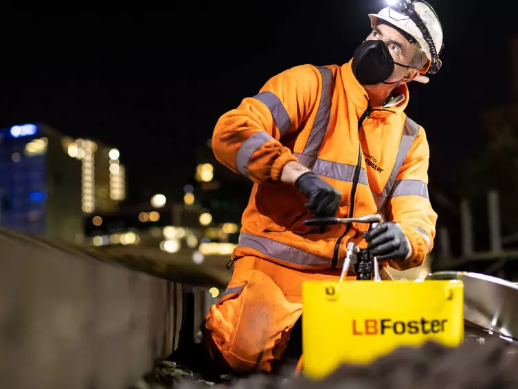 Man working on rail track at night, wearing protective mask and helmet.