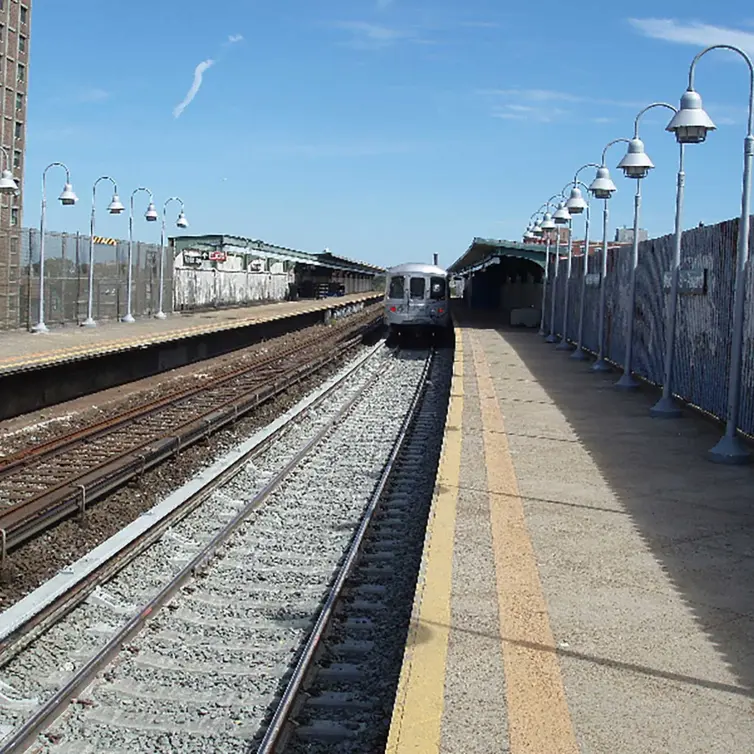 gare montrant la voie et le train à venir.
