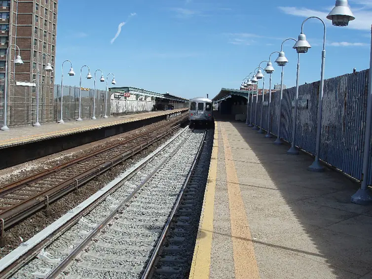 Bahnhof mit Gleisen und herannahendem Zug.
