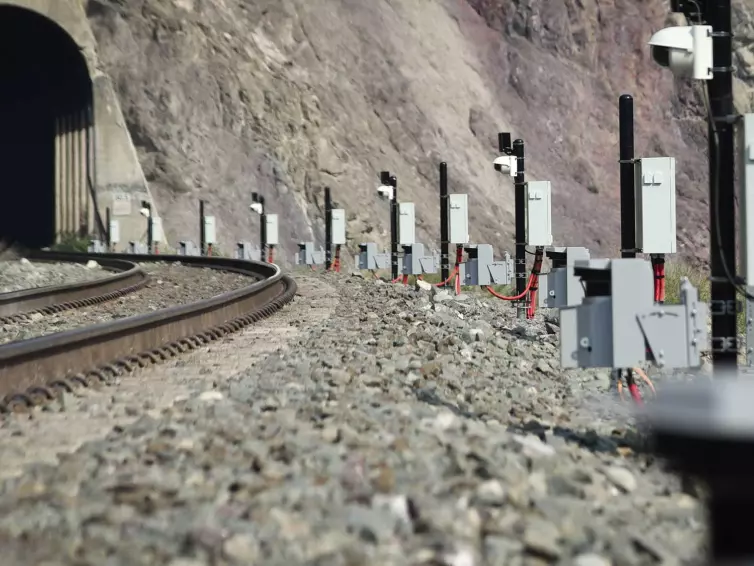 rockfall LiDAR installed next to a railroad track running through a tunnel in a mountainside.
