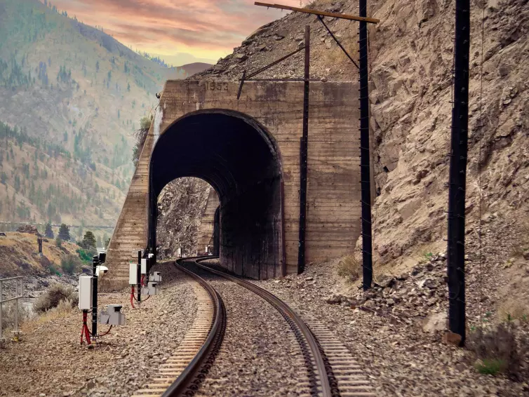 rockfall LiDAR installed next to a railroad track running through a tunnel in a mountainside.