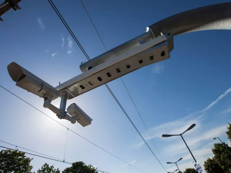 Câmeras de monitoramento de tráfego montadas em um poste de metal contra um céu azul claro.