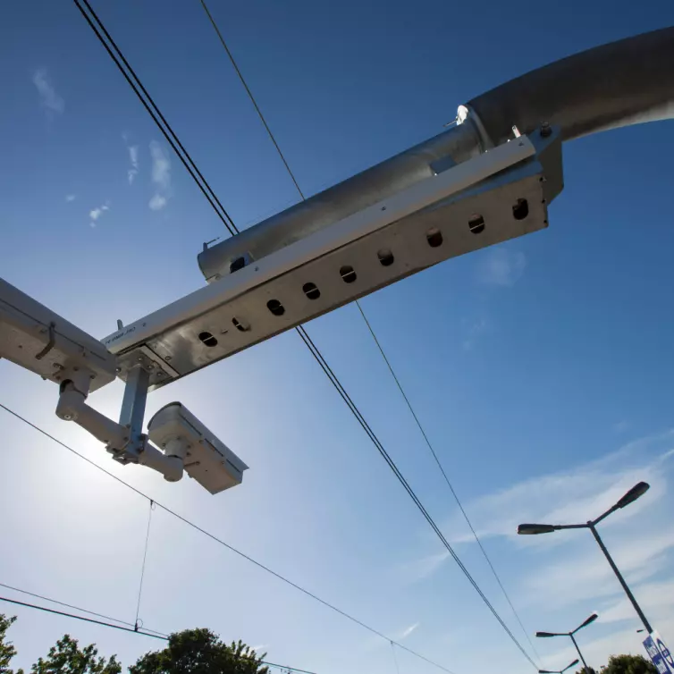 Cámaras de vigilancia del tráfico montadas en un poste metálico contra un cielo azul despejado.