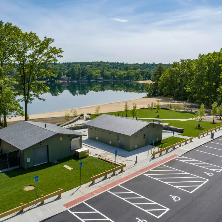 A serene lake scene featuring a parking lot and two buildings nestled nearby.