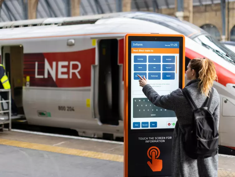 A woman is positioned next to a train, emphasizing her connection to travel and movement.