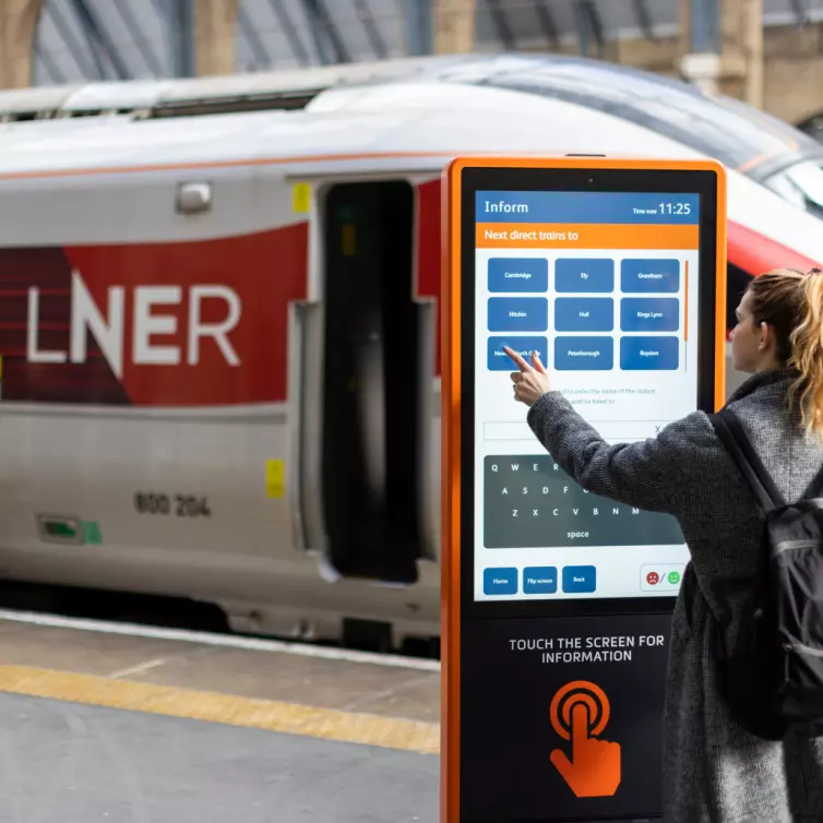 A woman is positioned next to a train, emphasizing her connection to travel and movement.